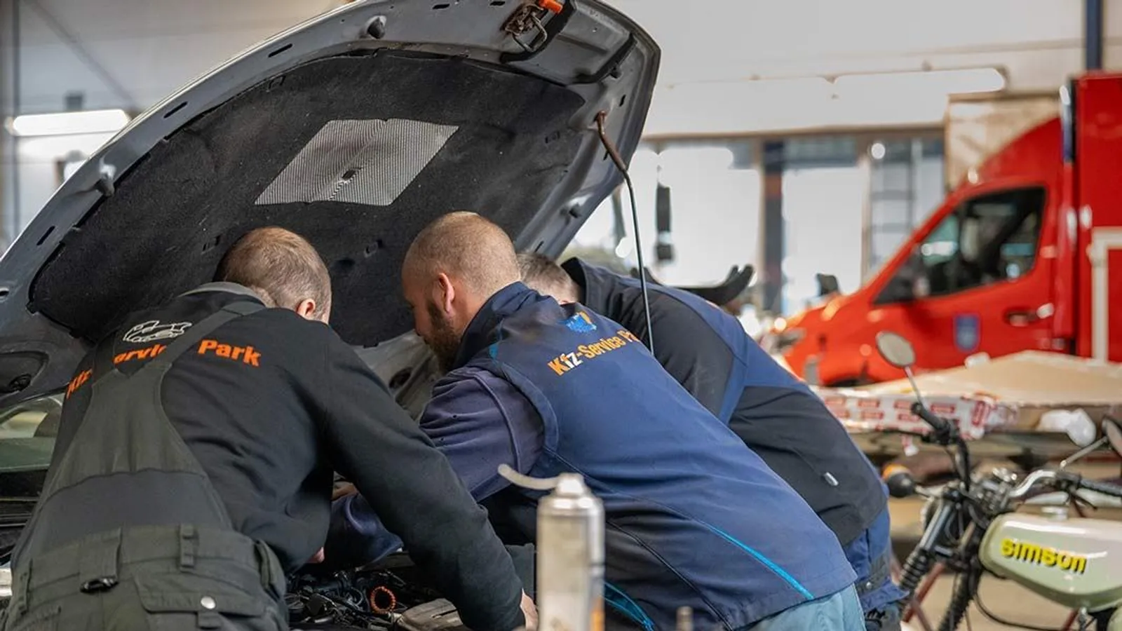 Zwei Monteure des Kfz-Service Park arbeiten in der Werkstatt in Naunhof am geöffneten Motorraum eines Fahrzeugs
